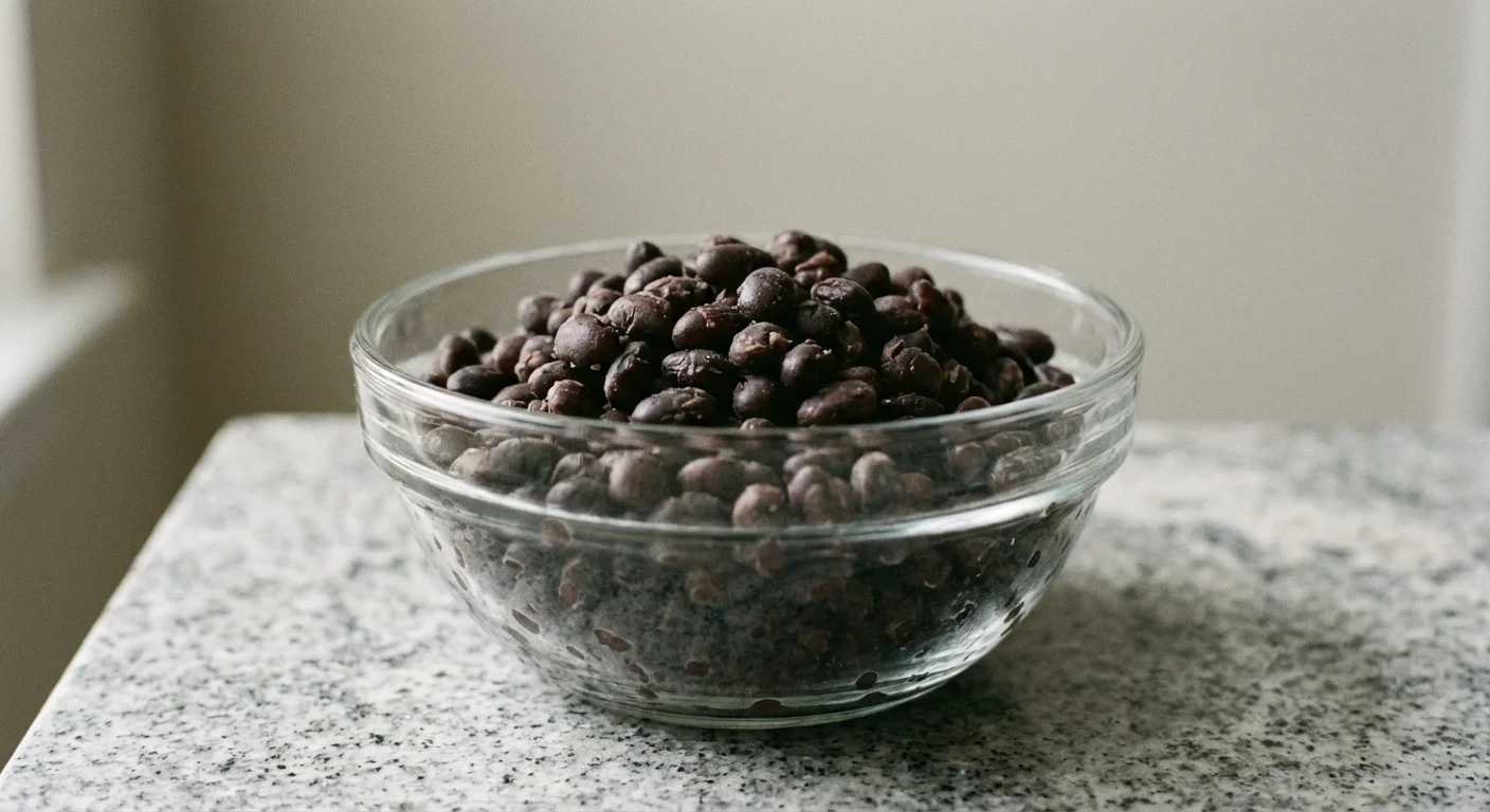 Close-up of black beans with a soft, slightly mushy texture in a glass bowl.