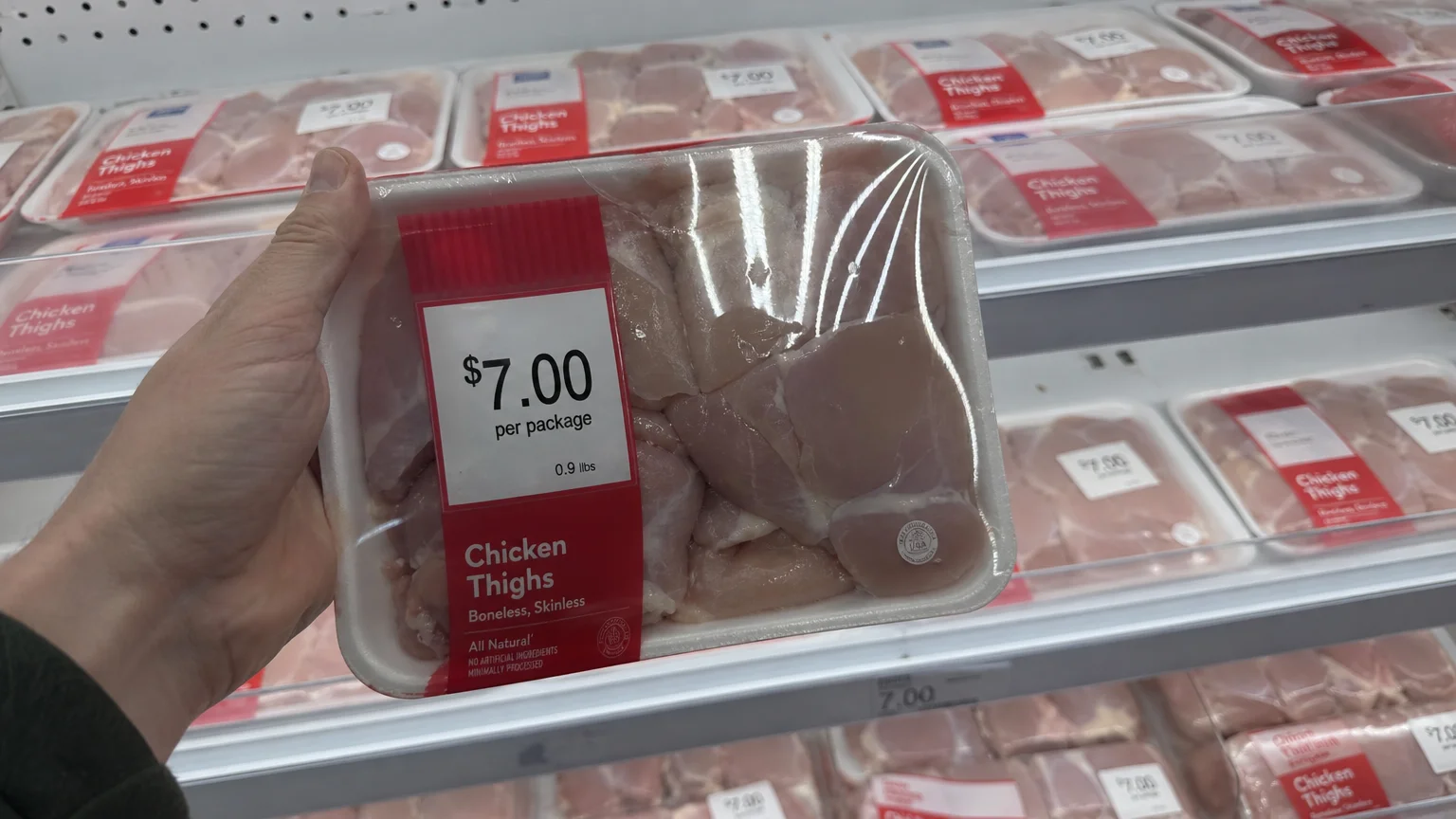 A close-up of a pre-packaged meat tray at a grocery store showing a fixed price for a weight under one pound.