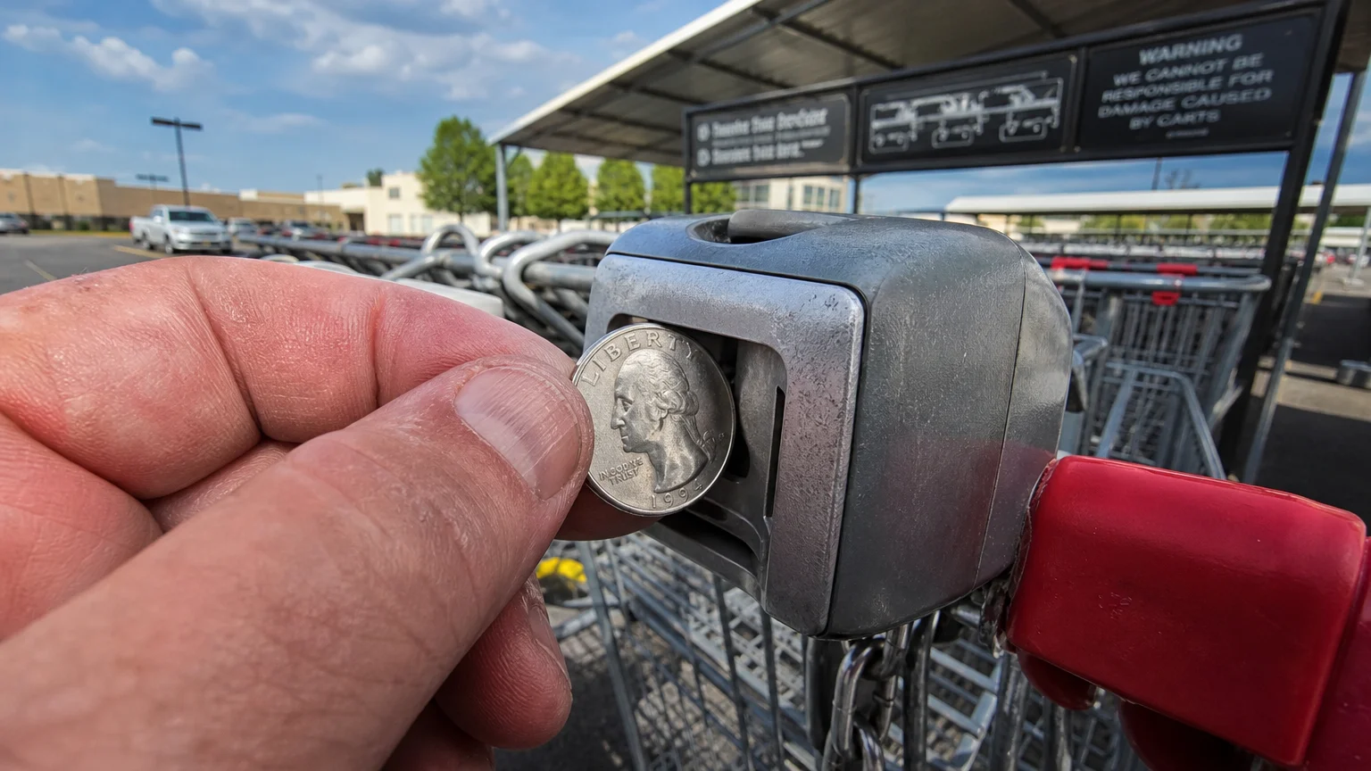 Close-up of a hand inserting a quarter coin into an Aldi shopping cart lock.